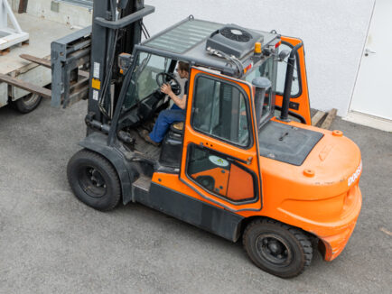 Chariot élévateur orange conduit par un salarié d’OACA